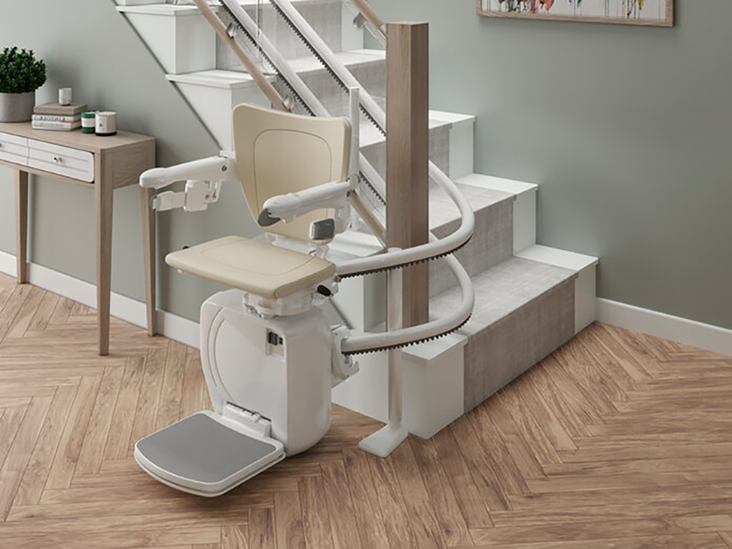 A curved stairlift with a twin track installation, parked at the foot of the stairs with a 180 degree parking bend